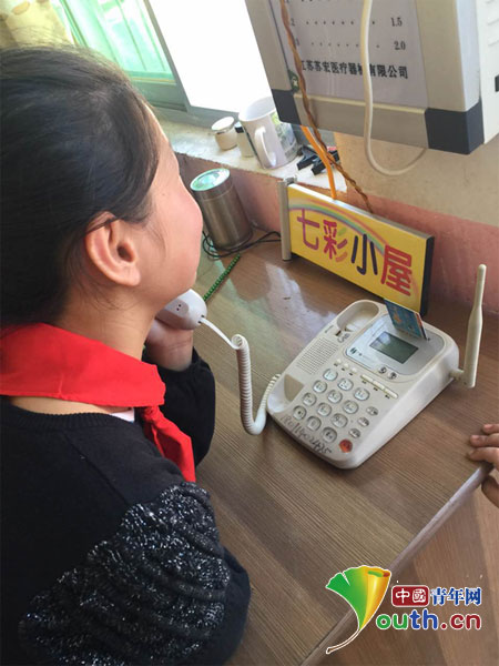 圖為一位小女孩與在外打工的父親通電話。周海淵供圖 圖為一位小女孩與在外打工的父親通電話。周海淵供圖